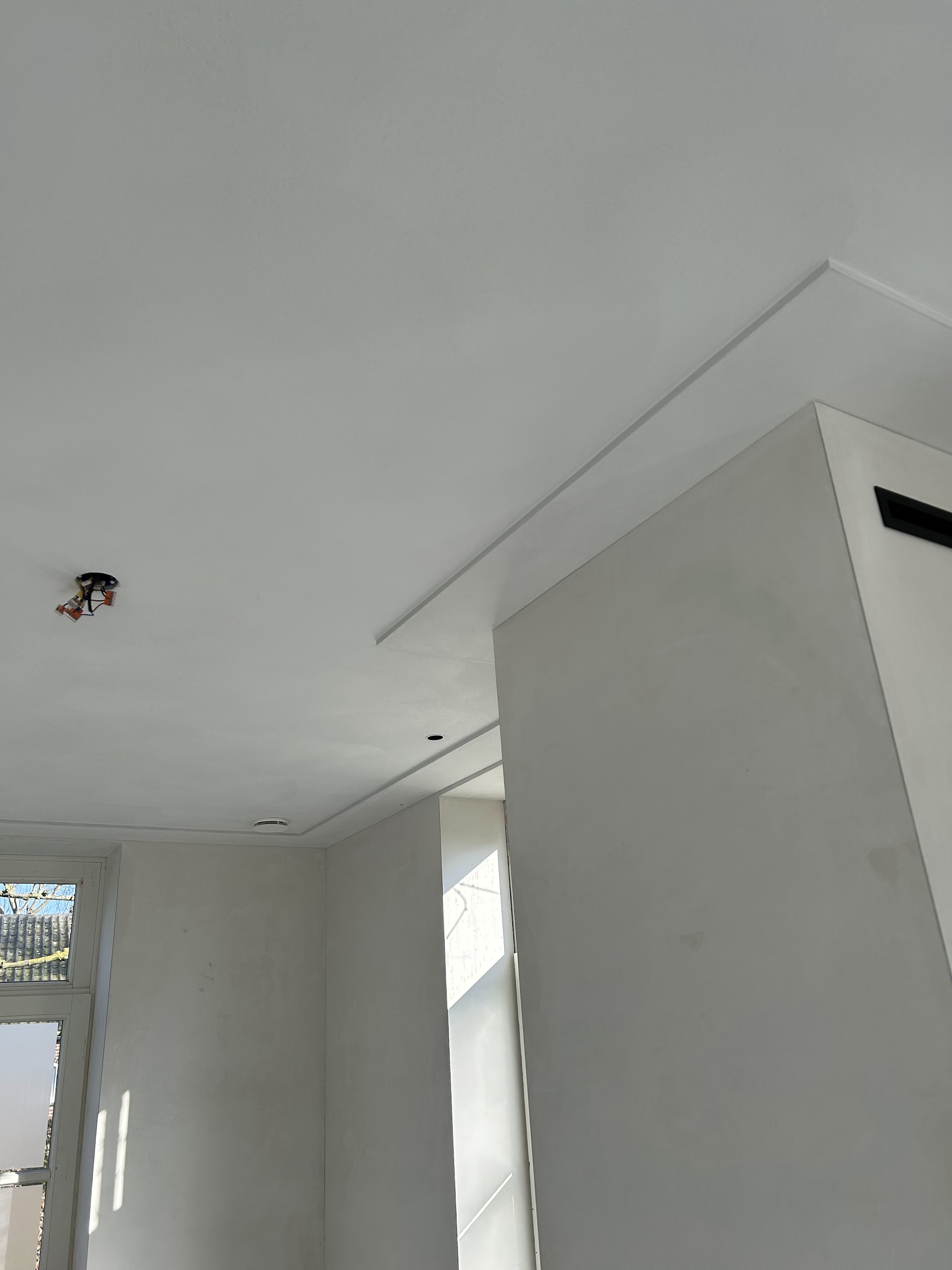 Gestuct plafond met een lijst langs een uitsprong in de muur