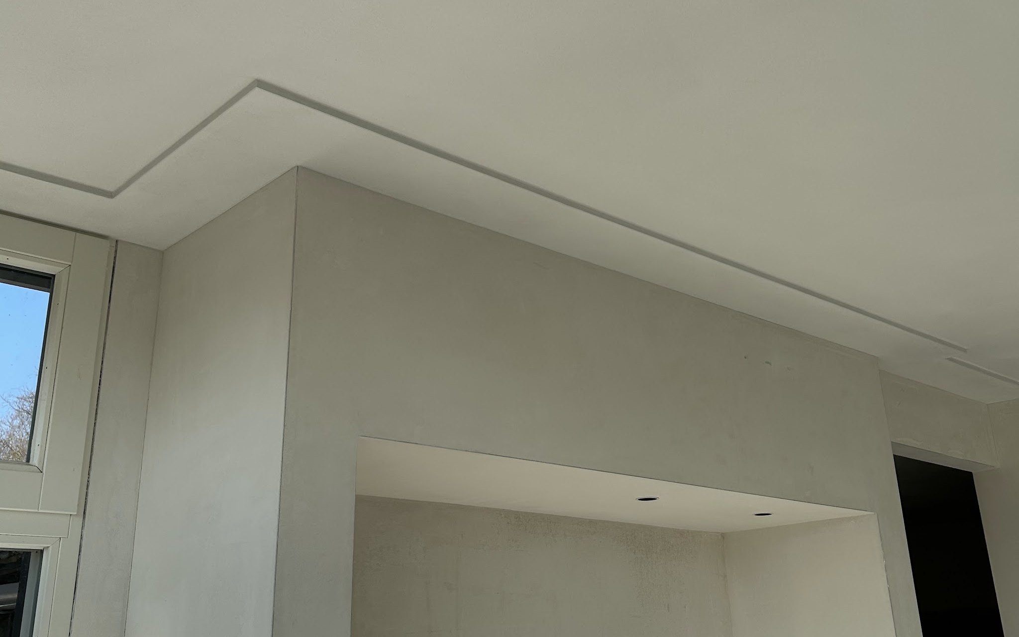 Vers gestucte nis onder een plafond met een strakke lijst